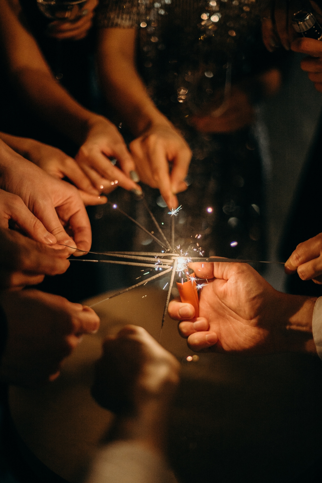 Eine Gruppe von Menschen, die Wunderkerzen eng beieinander halten, erzeugt vor einem dunklen Hintergrund ein helles und festliches Lichtspiel. Mehrere Hände sind sichtbar, was auf eine fröhliche Familienfeier oder ein feierliches Ereignis schließen lässt. Hotel Schloss Burgellern